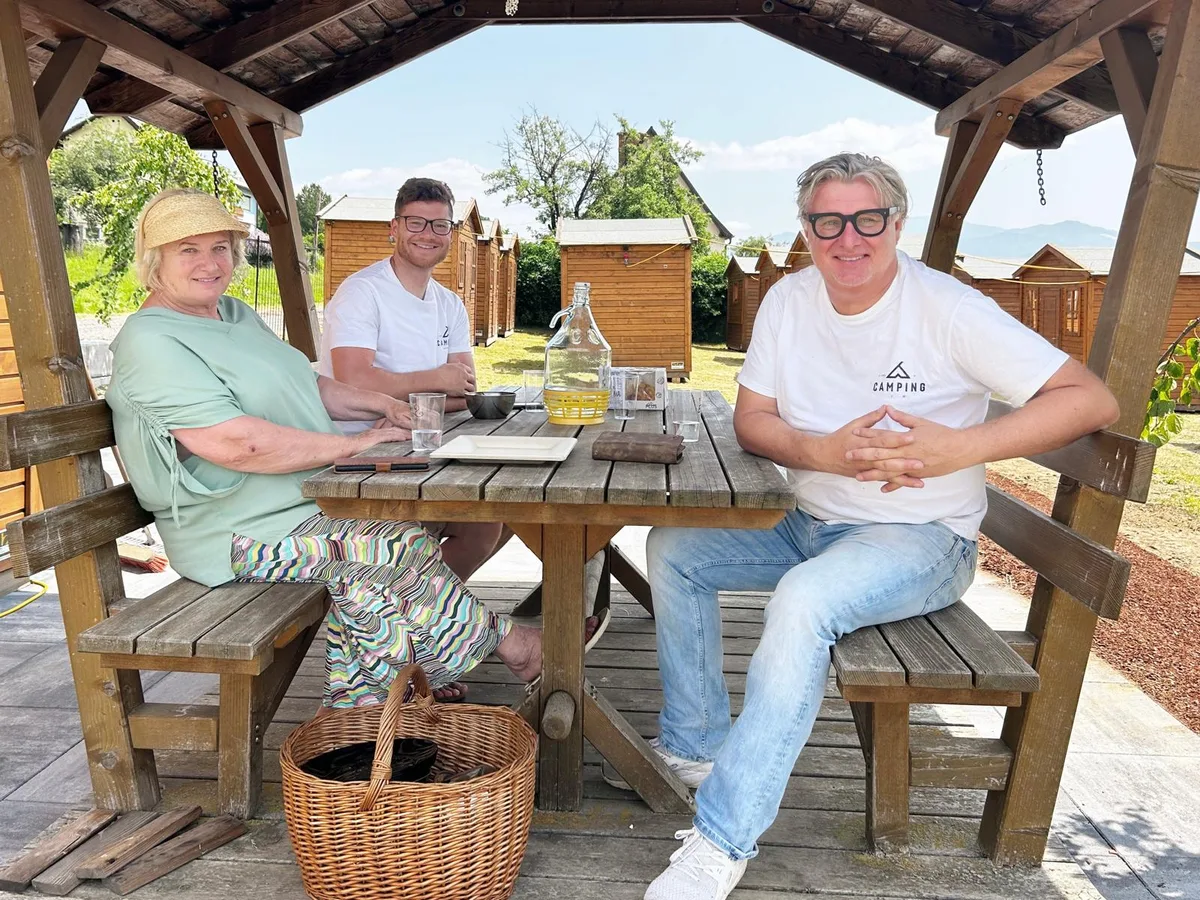 Sigrid, Philipp und Ekkehard Schitter im Pavillon vor den Holzchalets am Schitterhof CAMPING WEISS